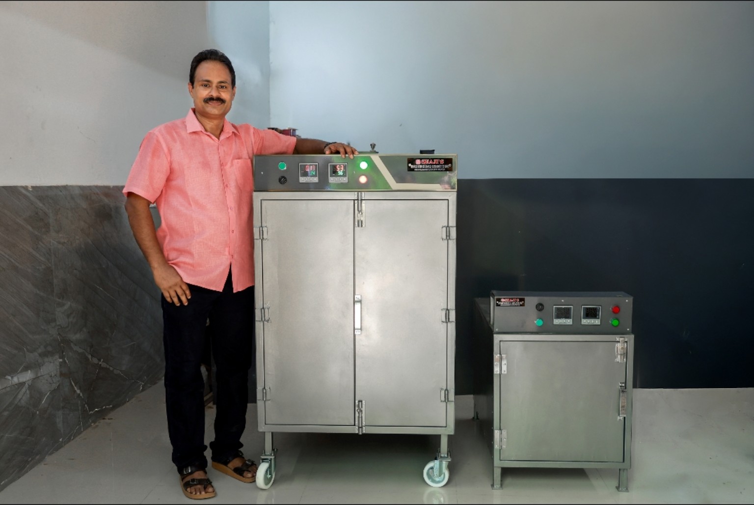 Owner of Shajis Engineering Industries standing beside two drying machines